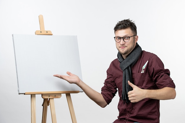 Front view young male painter along with easel on white background