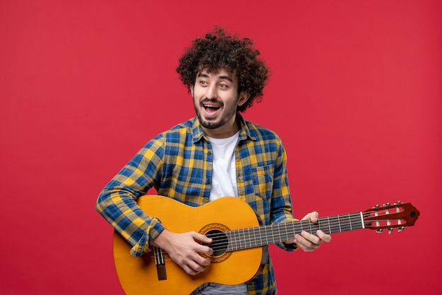 Front view young male playing guitar on red wall concert live color band music play musician