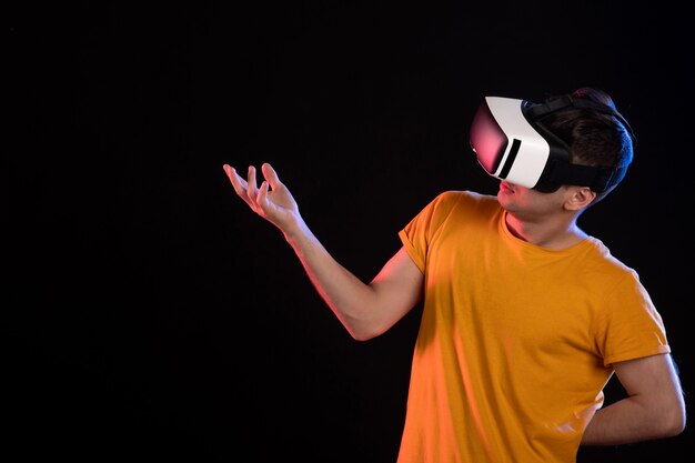 Front view of young male playing virtual reality on dark wall