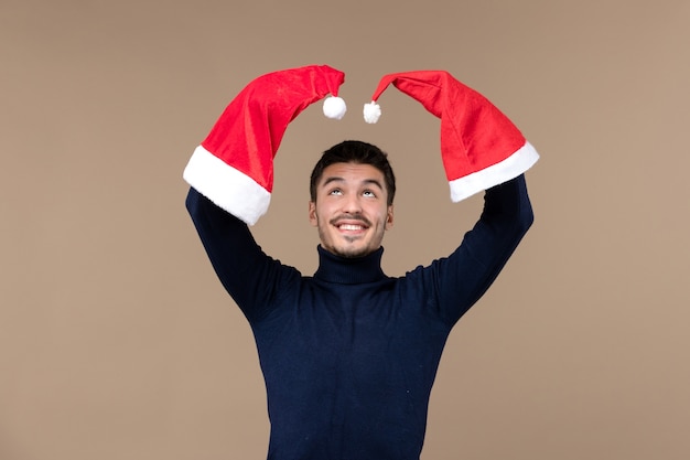 Front view young male playing with red caps on brown background emotion christmas holiday