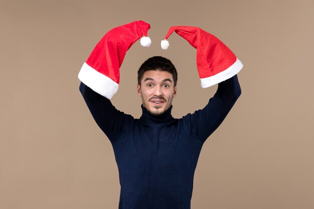 Front view young male playing with red caps on brown background emotions christmas holiday