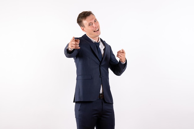Front view young male pointing in classic strict suit on white background