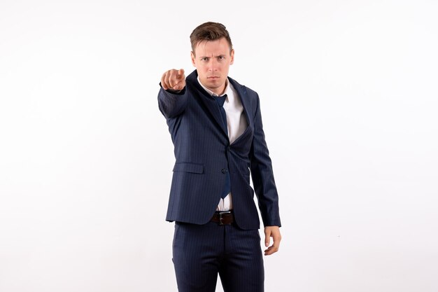 Front view young male pointing in classic suit on white background