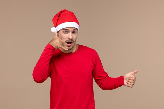 Вид спереди молодой мужчина позирует на коричневом фоне рождественский праздник эмоции