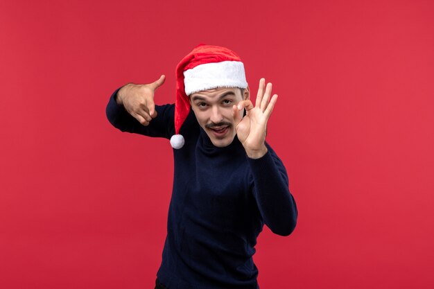 Front view young male posing with new year cap on red background