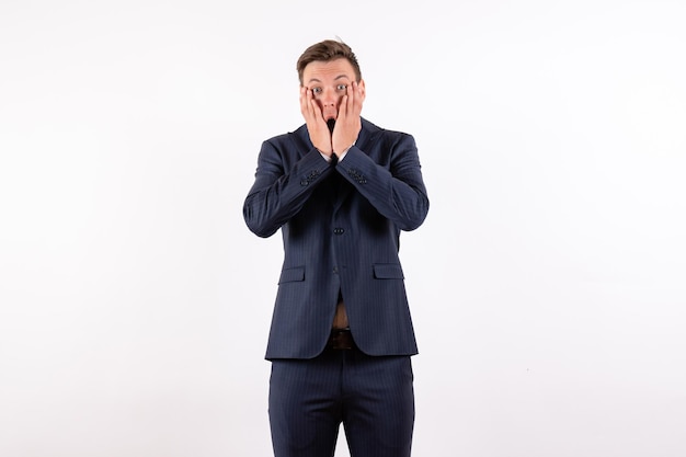 Front view young male posing with shocked face in classic strict suit on white background