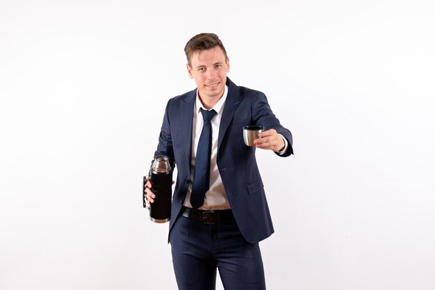 Front view young male pouring water from thermos in classic suit on a white background