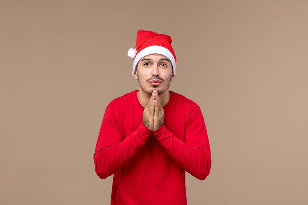 Front view young male praying on the brown background christmas emotion holiday