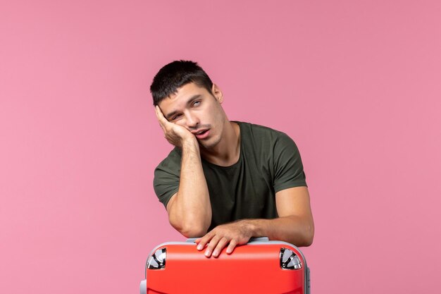 Front view young male preparing for trip and feeling tired on the pink space