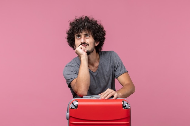 Front view young male preparing for trip on a pink desk