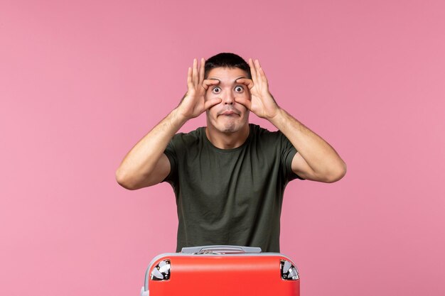 Front view young male preparing for trip widely opening his eyes on a pink space