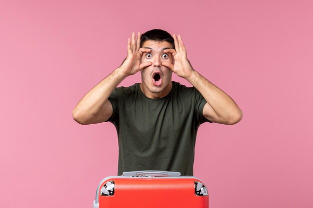 Front view young male preparing for trip widely opening his eyes on pink space