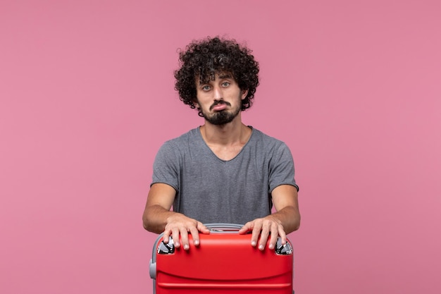 Front view young male preparing for trip with bag on pink desk