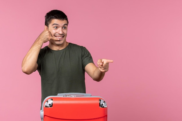 Front view young male preparing for trip with red bag on light pink space