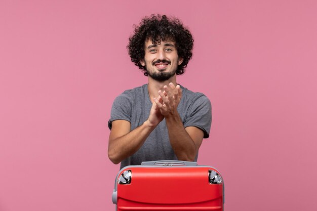 Front view young male preparing for vacation and clapping on pink space