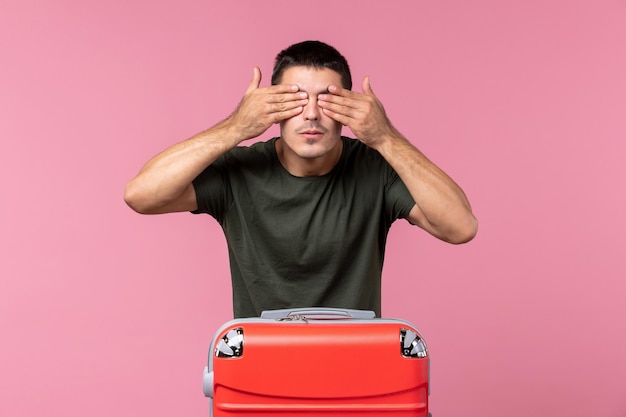 Front view young male preparing for vacation and covering his eyes on pink space