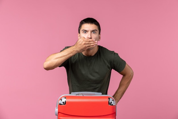 Front view young male preparing for vacation covering his mouth on pink space