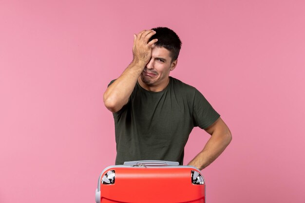 Front view young male preparing for vacation and crying on pink desk