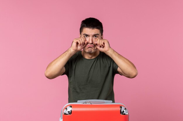 Front view young male preparing for vacation and crying on pink space