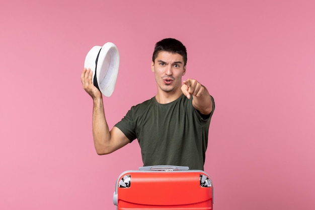 Free photo front view young male preparing for vacation holding hat on pink floor trip man journey voyage plane sea