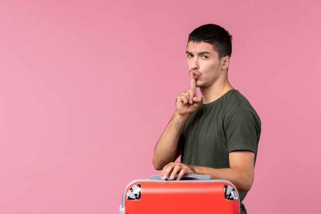 Front view young male preparing for vacation and showing silence sign on pink space