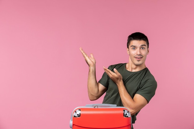 Front view young male preparing for vacation with big bag on pink space