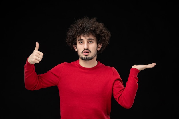 Front view of young male in red shirt on black wall