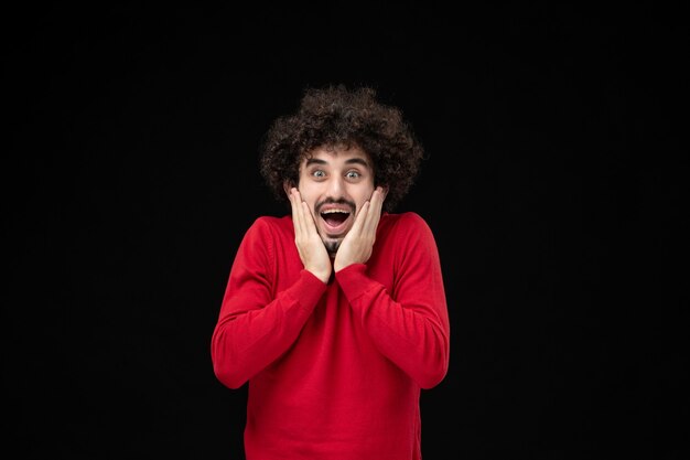 Front view of young male in red shirt on black wall