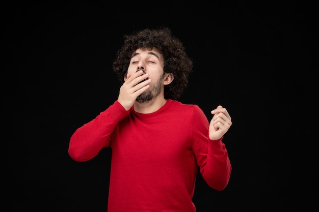 Front view of young male in red shirt on black wall