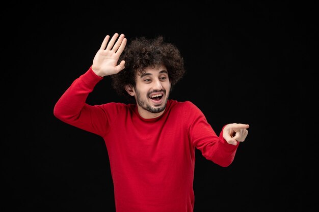 Front view of young male in red shirt on black wall