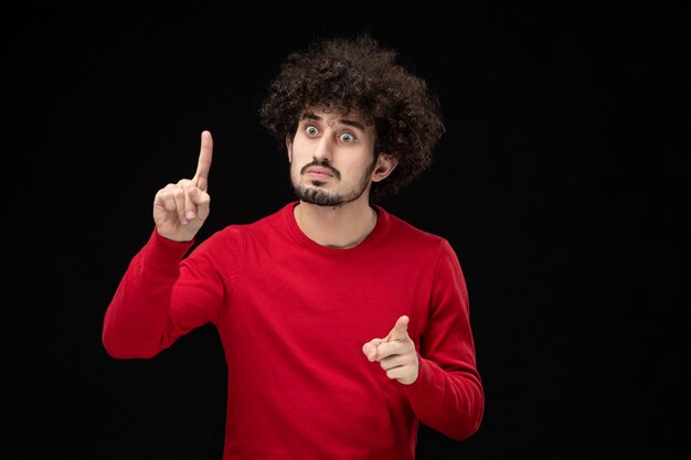 Front view of young male in red shirt on black wall