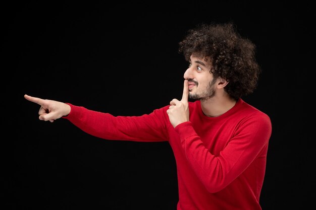 Front view of young male in red shirt on black wall