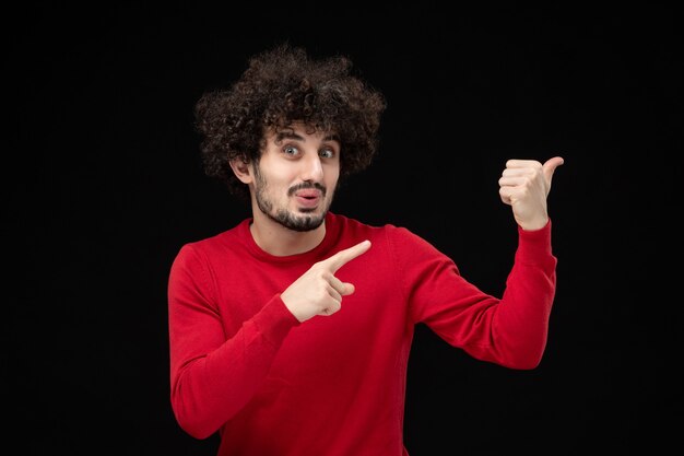 Front view of young male in red shirt on black wall