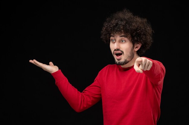 Front view of young male in red shirt on black wall