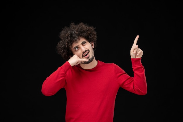 Front view of young male in red shirt on a black wall