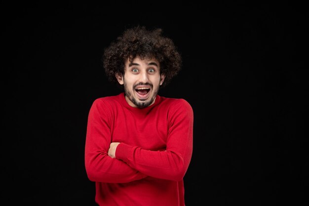 Front view of young male in red shirt on black wall