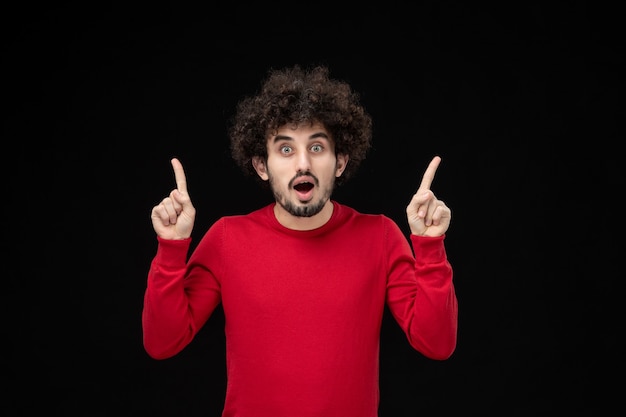 Front view of young male in red shirt on black wall