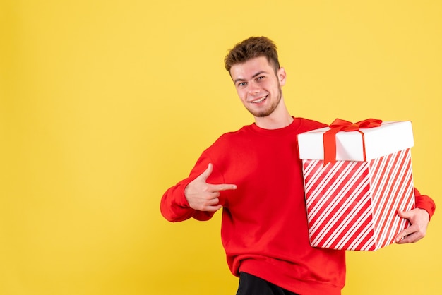 クリスマスプレゼントを保持している赤いシャツの正面図若い男性