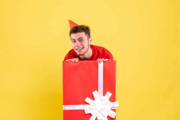 Front view young male in red shirt inside present box smiling