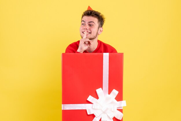 Front view young male in red shirt sitting inside present box