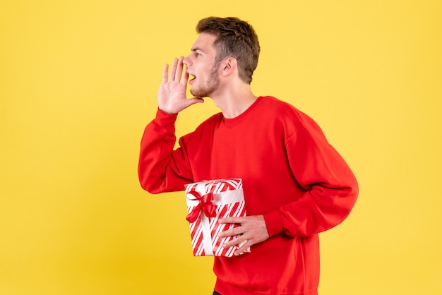 Front view young male in red shirt with christmas present calling