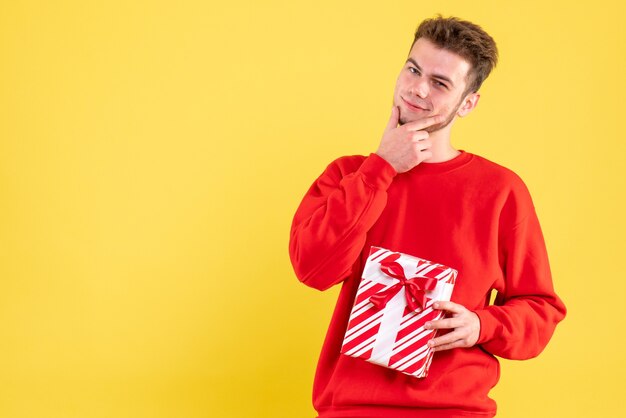クリスマスプレゼントのポーズと赤いシャツの正面図若い男性