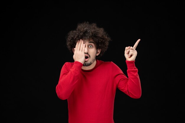 Front view of young male in red sweater on black wall