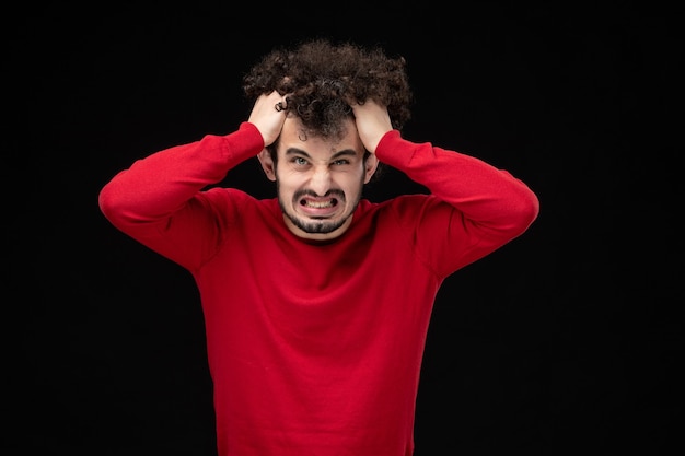 Free photo front view of young male in red sweater on black wall