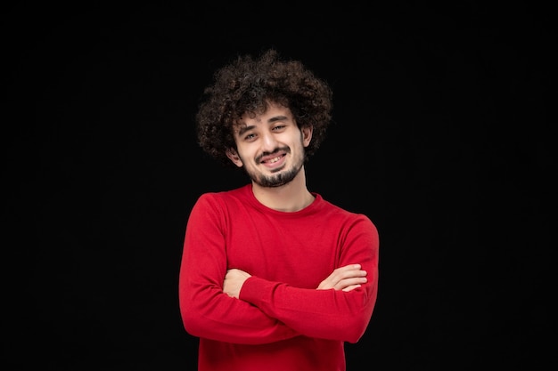 Front view of young male in red sweater on black wall