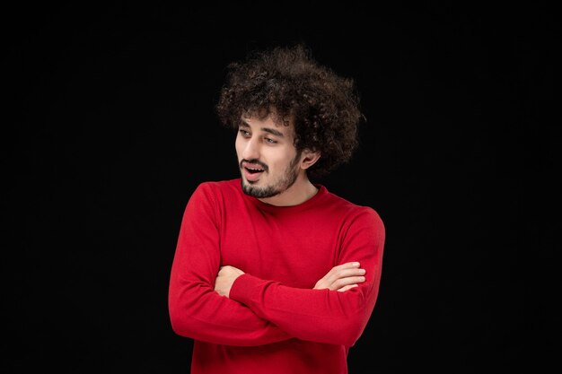 Front view of young male in red sweater on the black wall