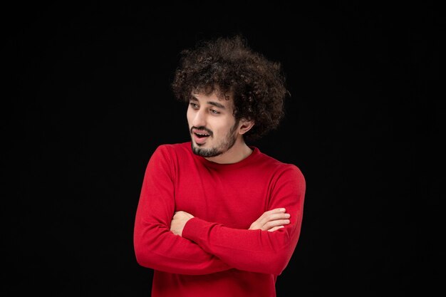 검은 벽에 빨간 스웨터를 입은 젊은 남성의 전면 모습