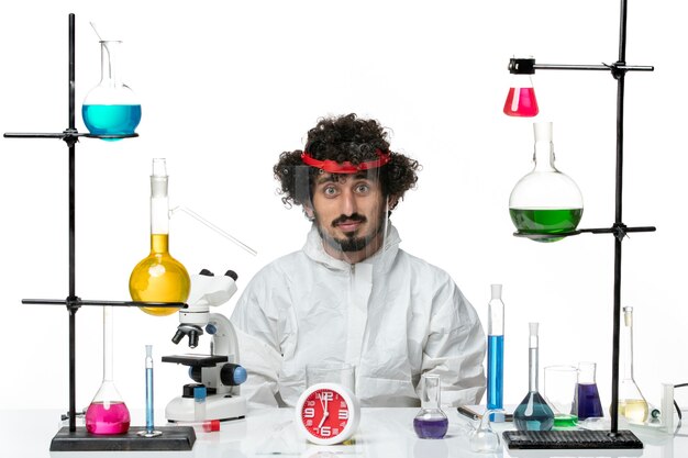 Front view young male scientist in special suit wearing special protective helmet on white background 