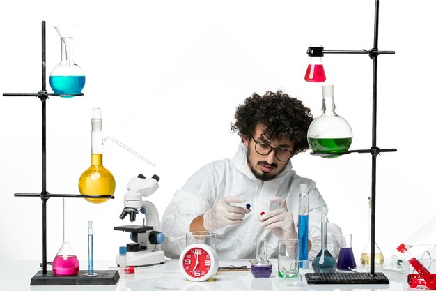 Вид спереди молодой ученый-мужчина в специальном костюме в рабочем процессе на белой стене