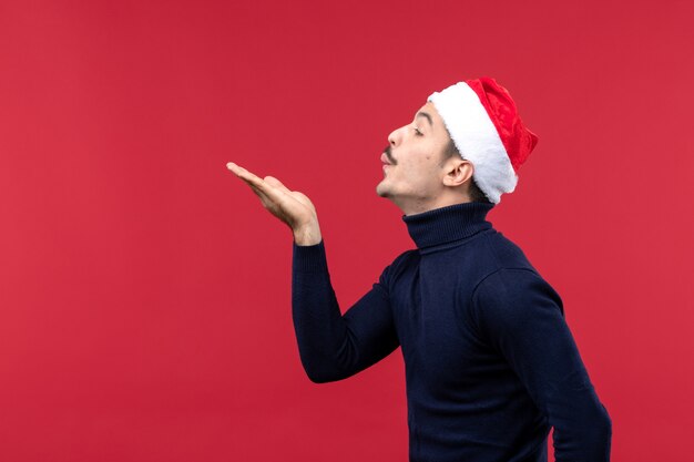 Free photo front view young male sending air kisses on a red background